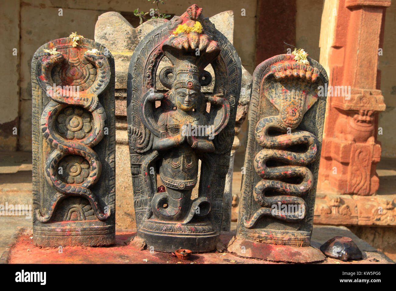 I devoti mettere vermiglio su idoli del serpente dèi a Yoga Narasimha tempio in Nandi colline nei pressi di Bengaluru, Karnataka, India, Asia Foto Stock