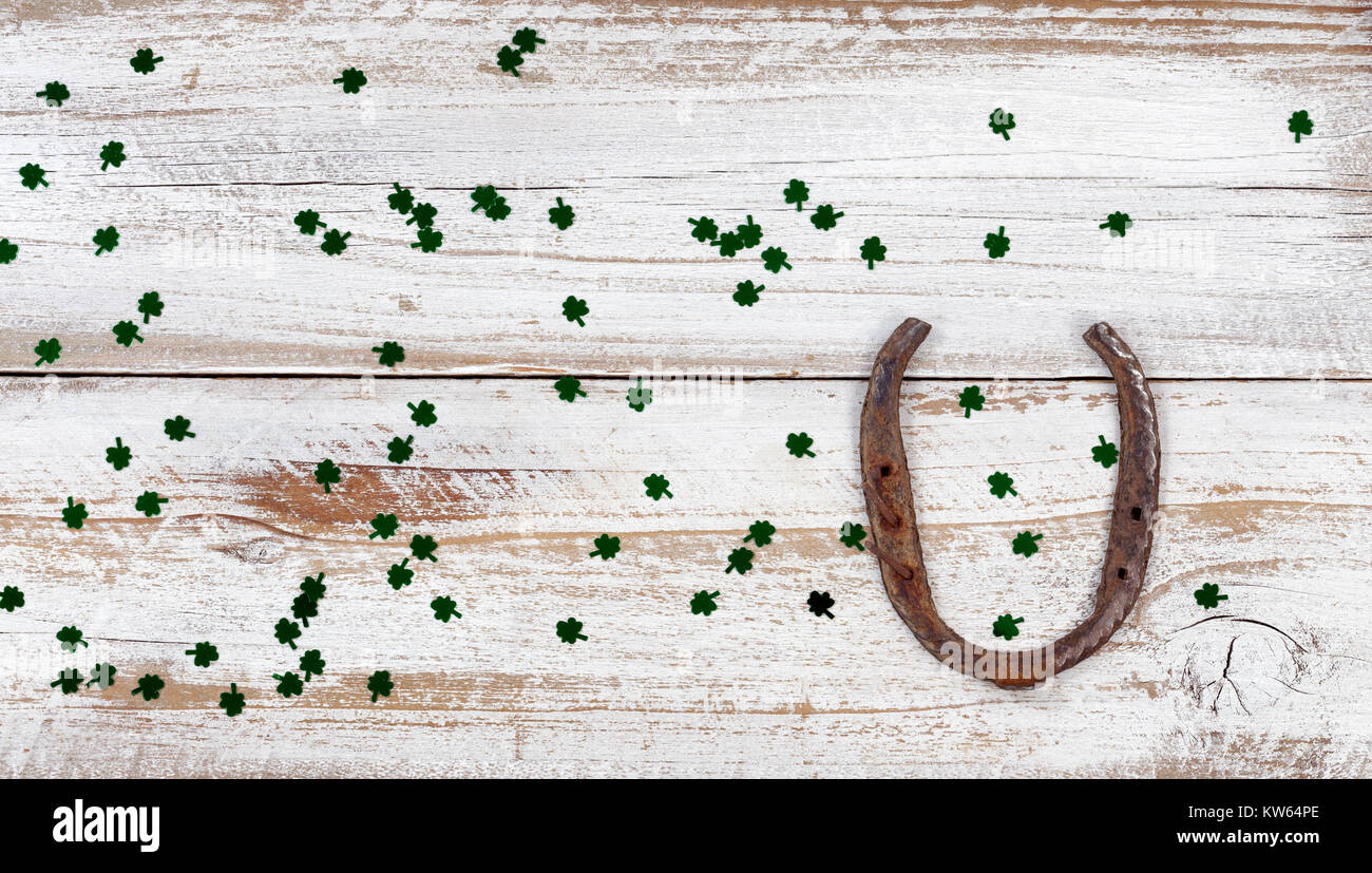 San Patrizio giorno buona fortuna a ferro di cavallo con trifogli lucido su bianco rustico di tavole di legno in vista aerea Foto Stock