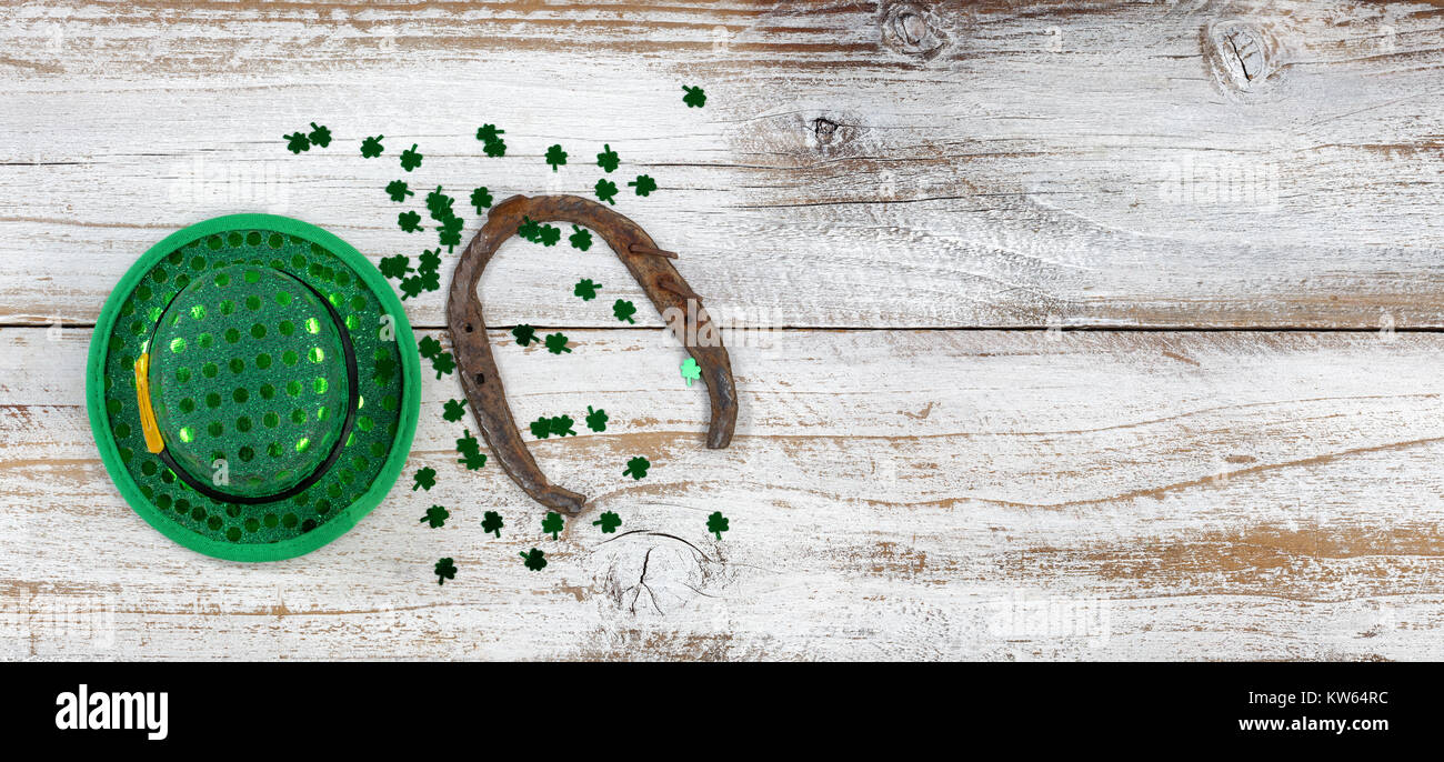 Il giorno di San Patrizio buona fortuna hat e a ferro di cavallo con trifogli su spiovente di legno bianco in vista aerea Foto Stock