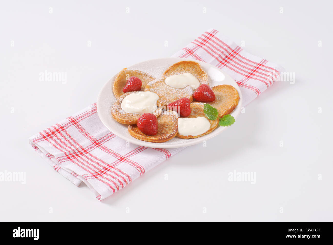 Piastra di piccole frittelle con panna montata e fragole Foto Stock
