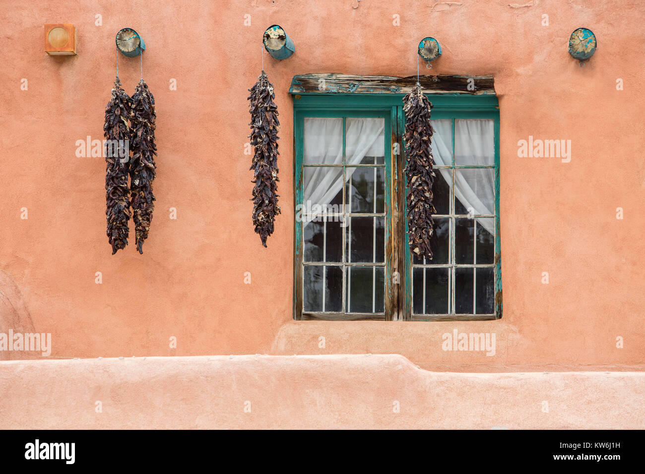 Peperoncino rosso ristras appeso su edifici adobe, UAT New Mexico Foto Stock