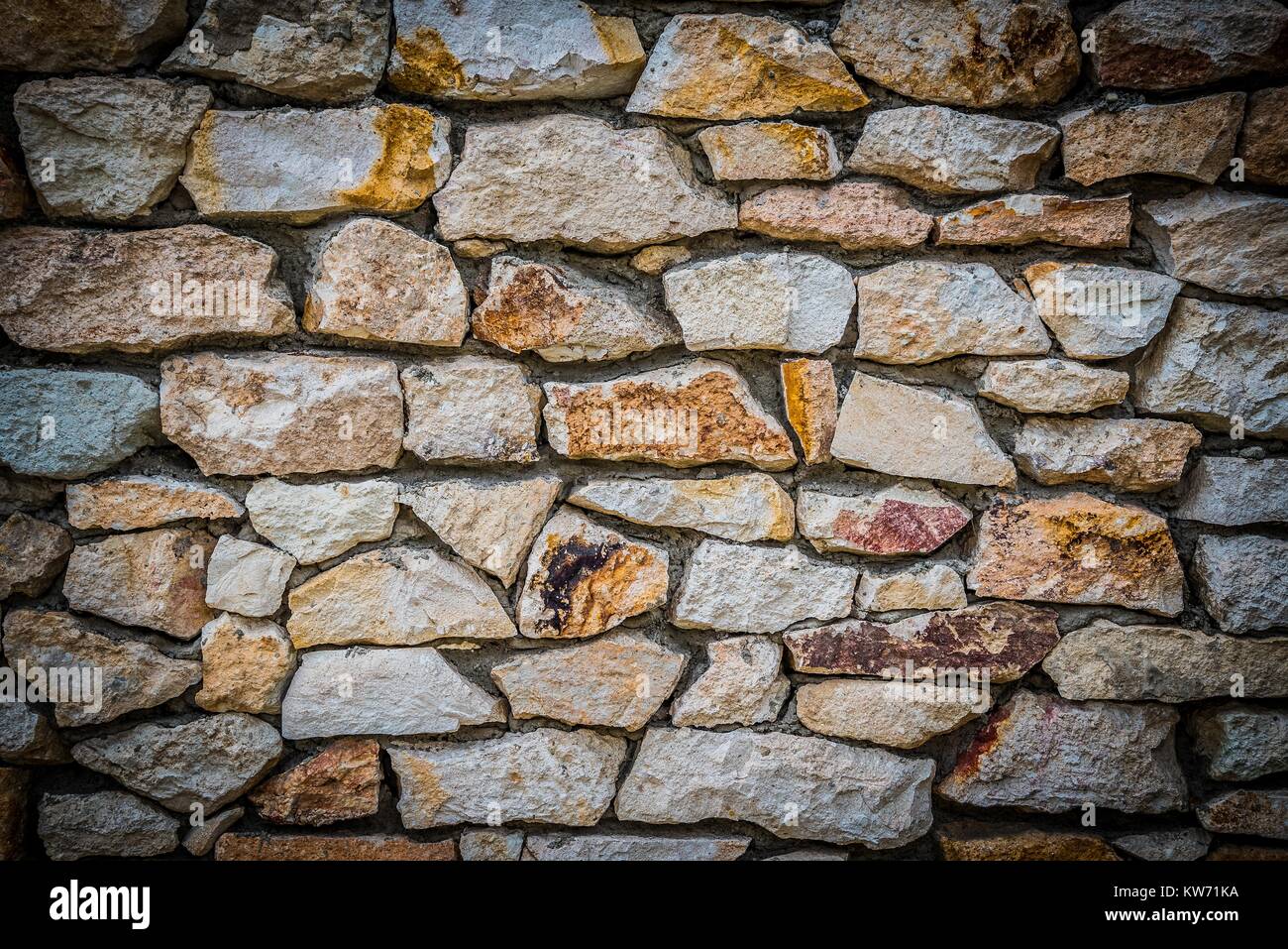 Muro di pietra sullo sfondo di pietre colorate con effetto HDR e frontiere vignettato Foto Stock