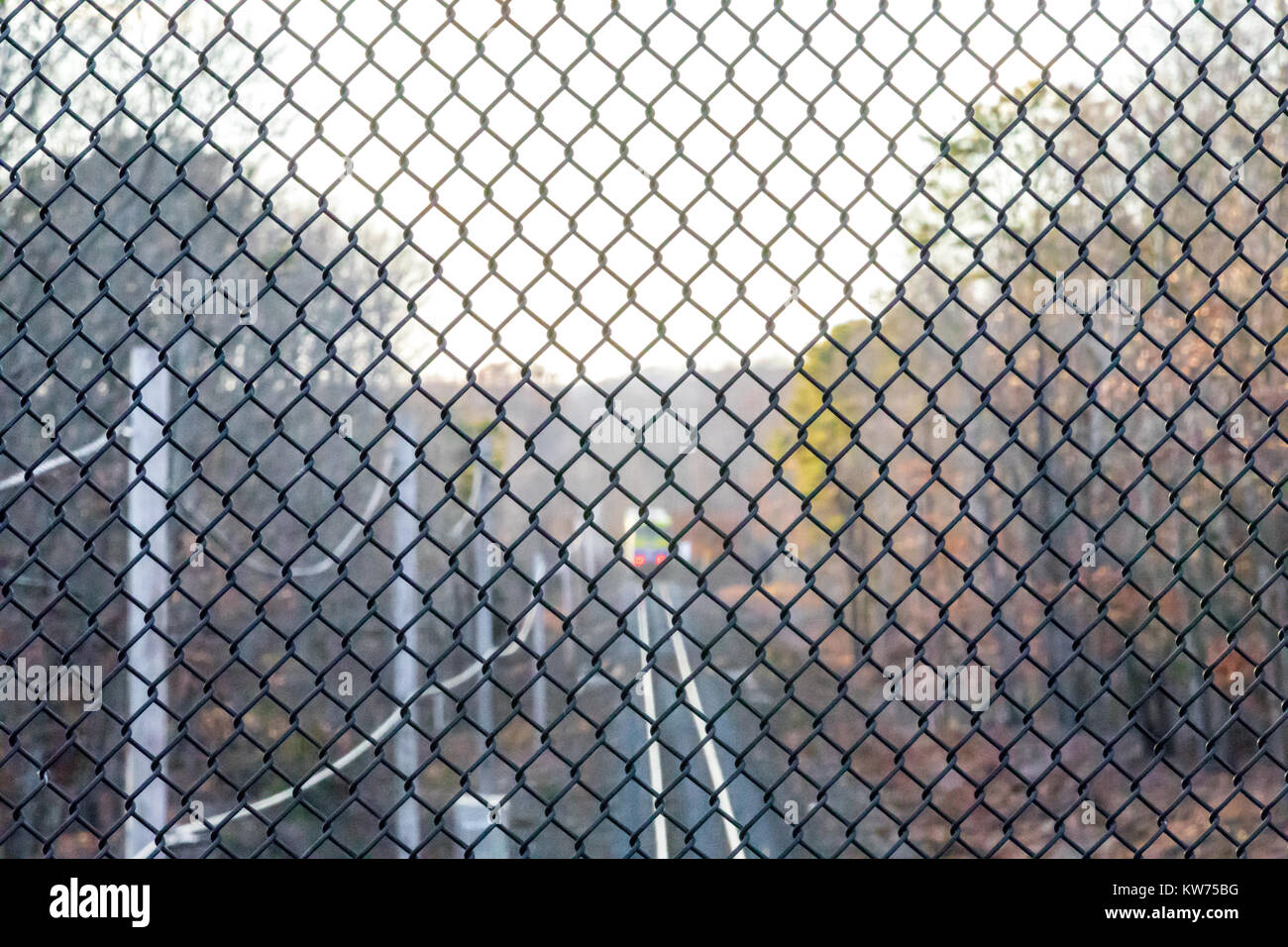 Vista di un treno da un alto punto di vantaggio attraverso una catena di recinzione di collegamento Foto Stock