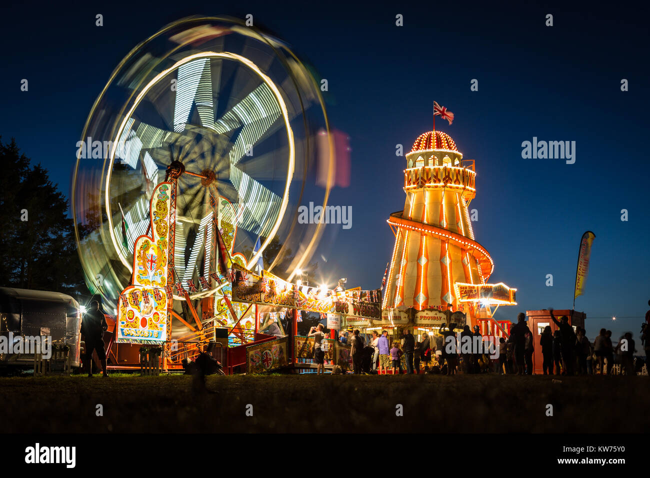 Una grande ruota e Helter Skelter accesa contro il cielo al crepuscolo Foto Stock