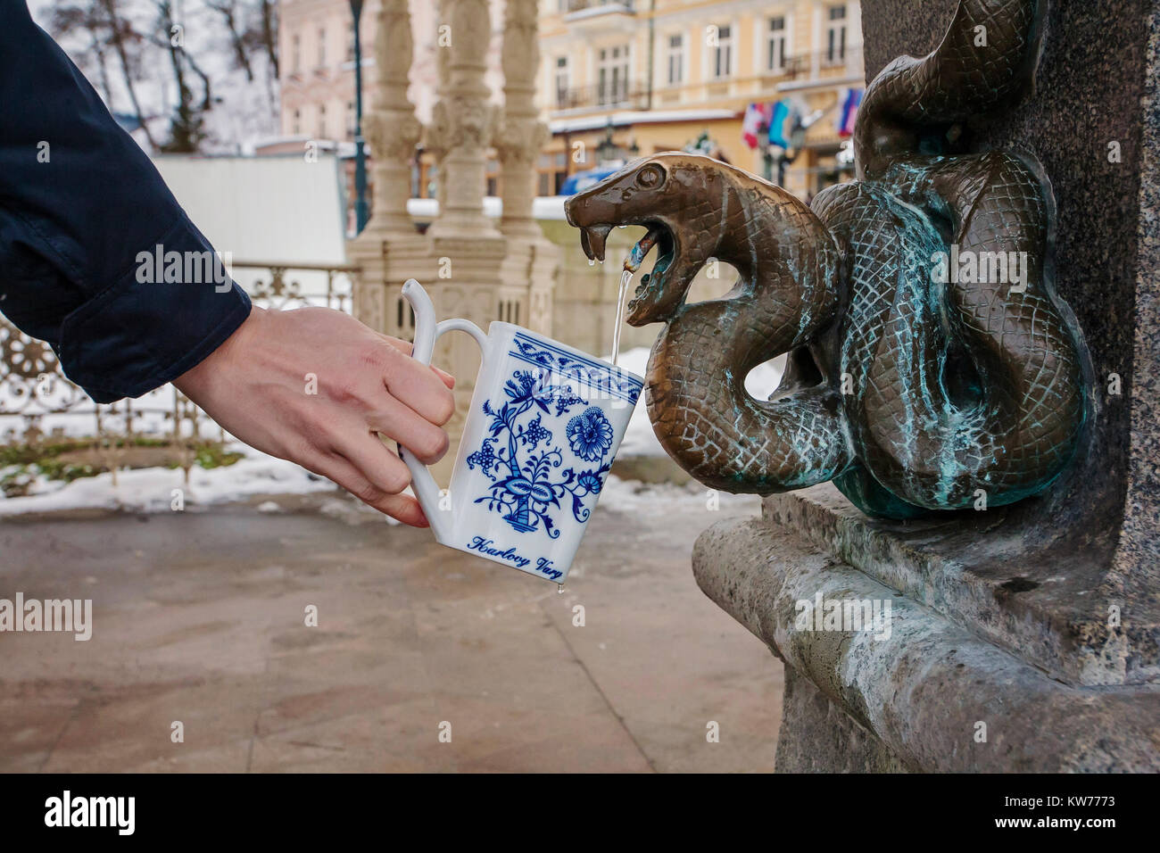 Mano riempire un bicchiere con acqua minerale terapeutica ad una sorgente calda naturale a Karlovy Vary durante il periodo invernale, Repubblica Ceca Foto Stock