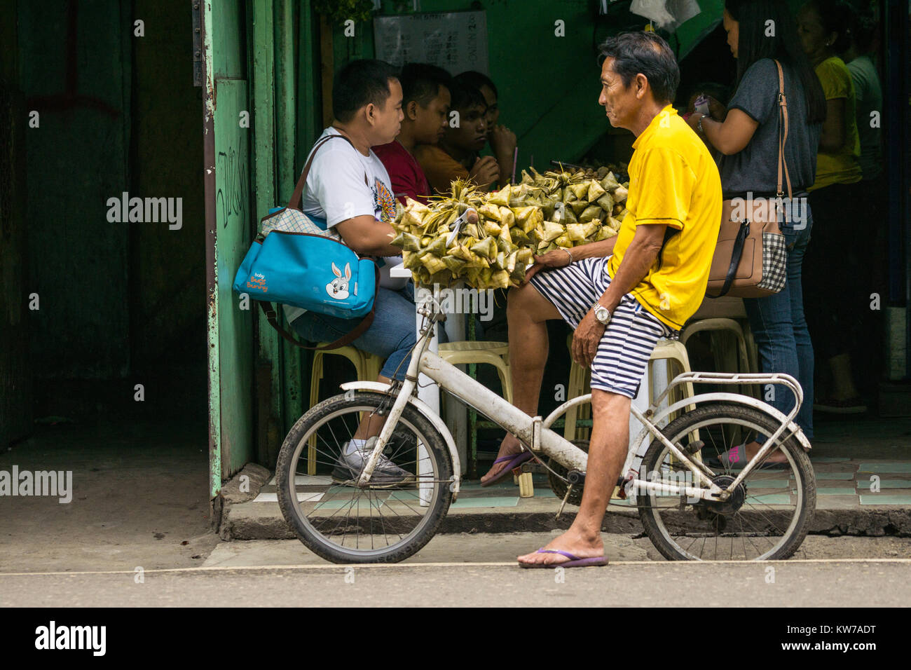 Un uomo su una bicicletta Puso di vendita,altrimenti noto come appendere il riso ai singoli punti di ristoro a Cebu City, Filippine Foto Stock