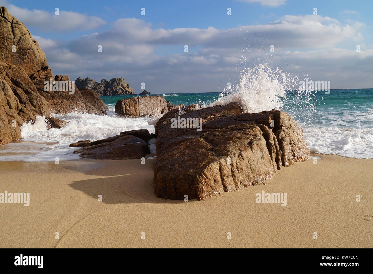 Onde che si infrangono su una grande roccia sulla spiaggia Porthcurno Foto Stock