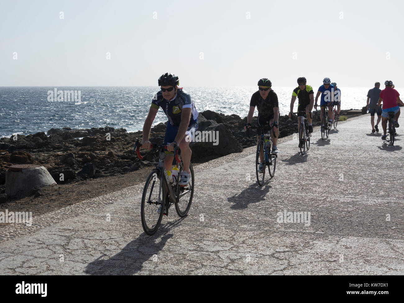 I ciclisti di fronte al mare sulla Costa Teguise, Lanzarote, Isole Canarie, Spagna. Foto Stock
