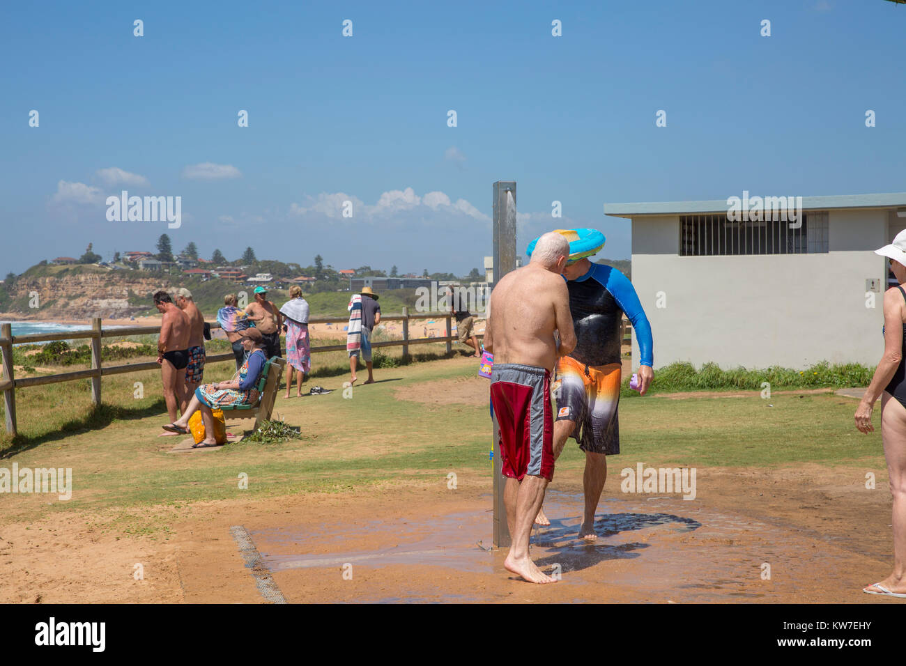 Gli uomini con la doccia spiaggia dopo una nuotata al Mona Vale Beach a nord di Sydney, Australia Foto Stock