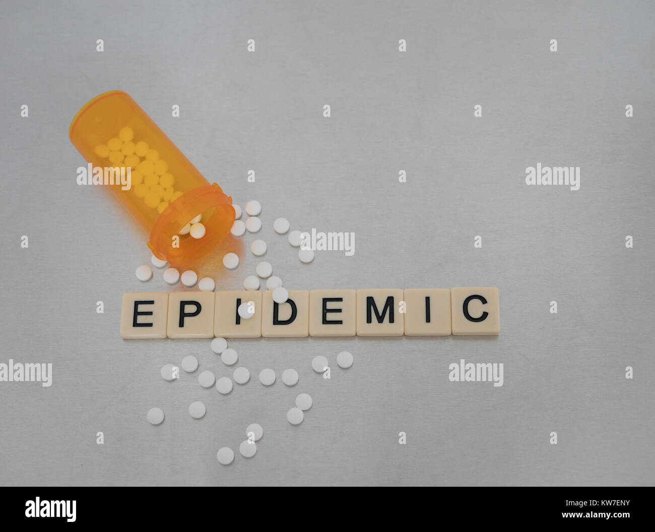 Epidemia scritto con lettere di piastrella in una riga con una bottiglia aperta di ossicodone pillole. Fotografato dal di sopra su un acciaio inossidabile sfondo. Foto Stock