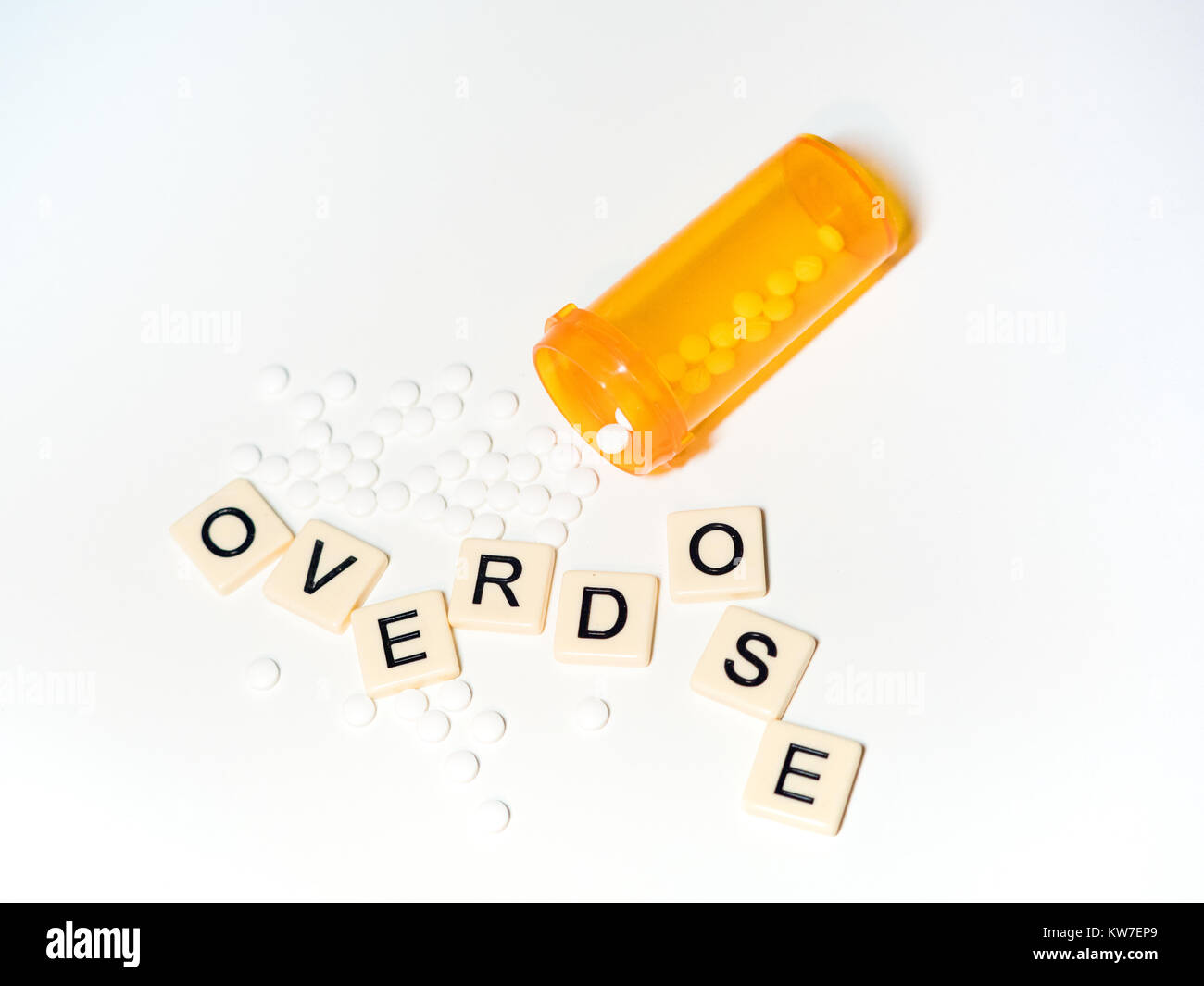 Overdose scritto con piastrelle casuale di lettere con piccole pillole di bianco e una prescrizione di aprire la bottiglia. Fotografato dal di sopra su uno sfondo bianco. Foto Stock