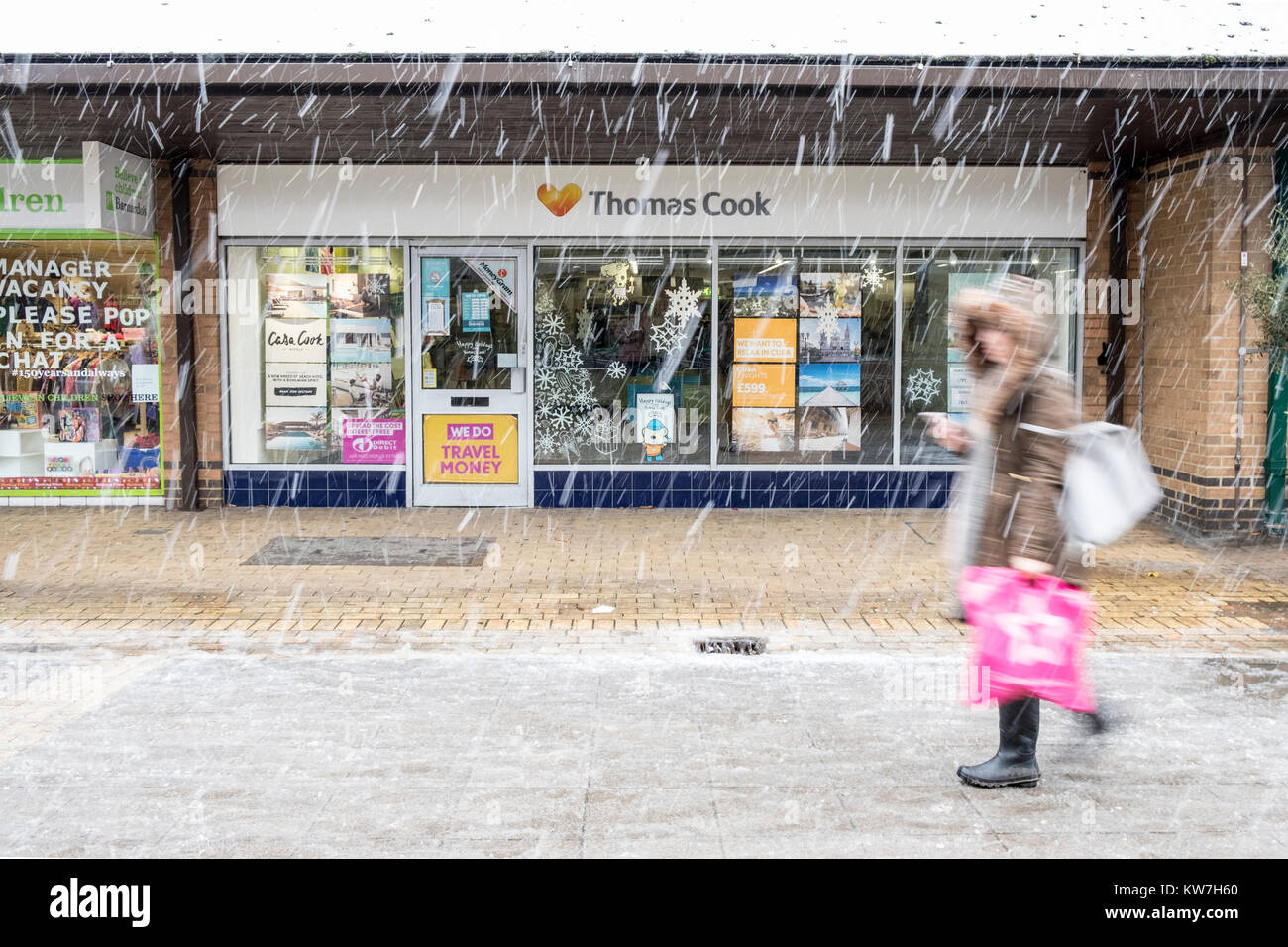 Donna cammina passato esterno del ramo della Thomas Cook Travel Agency in inverno la neve Foto Stock