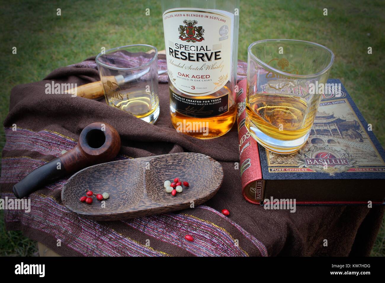Ancora vita fatta di bottiglie di whisky, due bicchieri, un libro e un tubo di legno e ciotola Foto Stock