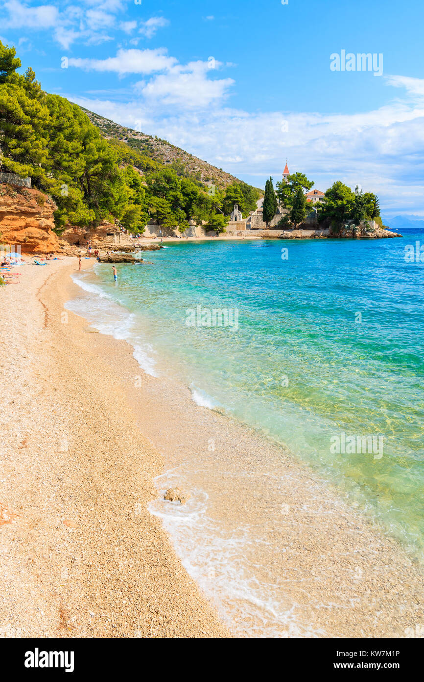 Bella spiaggia di ciottoli con acque turchesi e vista del monastero domenicano in distanza, città di Bol, isola di Brac, Croazia Foto Stock