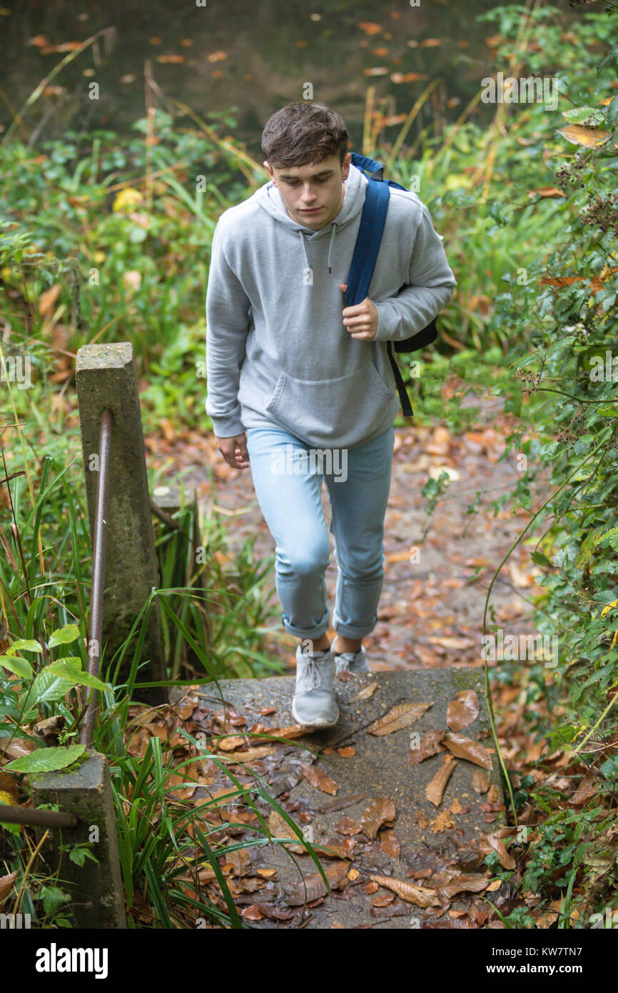 Ragazzo adolescente salire a piedi a passi concreti nei pressi di un canale in una giornata autunnale Foto Stock