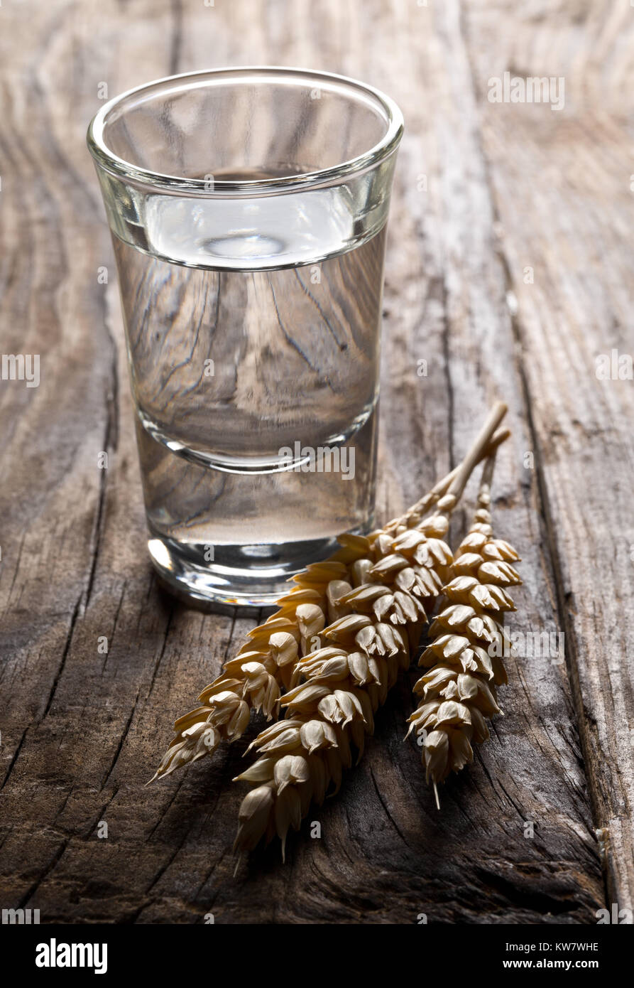 Disco tedesco liquore Grappa alla Korn nel colpo di vetro con spighe di grano su tavola in legno rustico Foto Stock