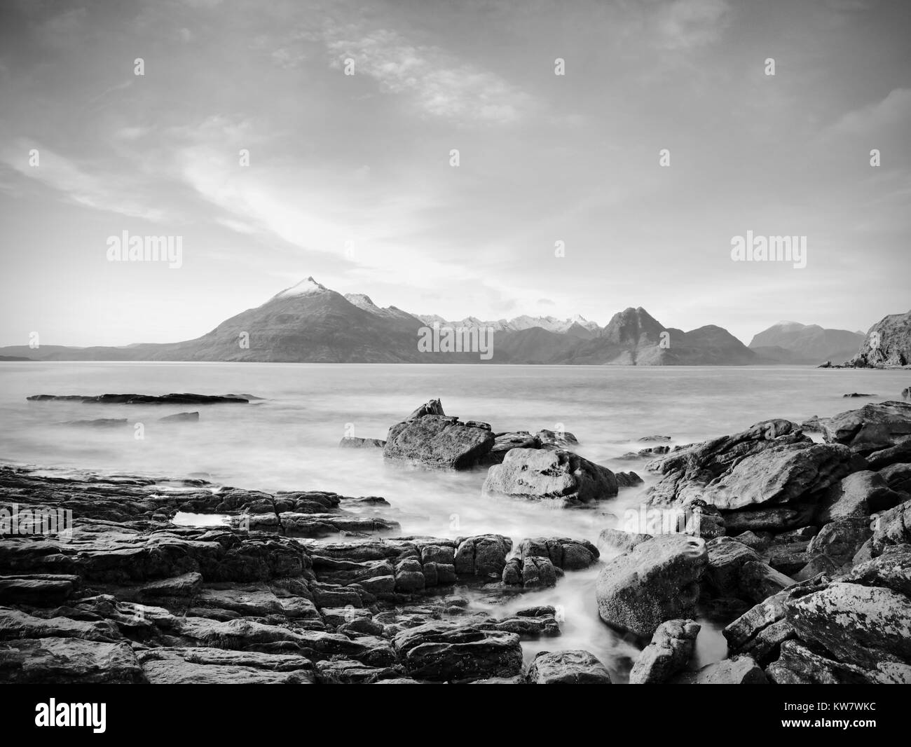 La spiaggia sassosa e scogliera della Baia rocciosa. Toni di blu di febbraio del tramonto, rosa orizzonte. Dark slipery massi con profonde spaccature. Foto Stock