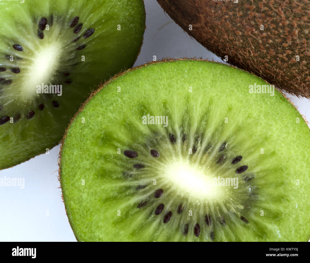 Kiwi verde tagliato a metà accanto a un intero isolato su sfondo bianco Foto Stock