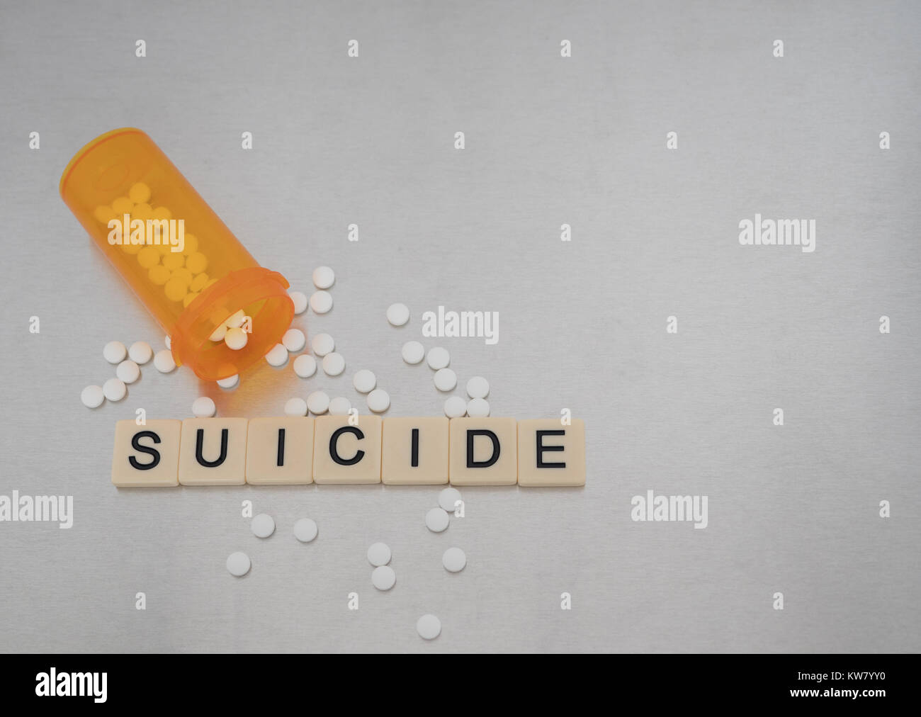 "Suicide' scritto con lettere di piastrelle collocato in una riga con una bottiglia aperta di pastiglie di ossicodone. Fotografato dal di sopra su un acciaio inossidabile sfondo. Foto Stock