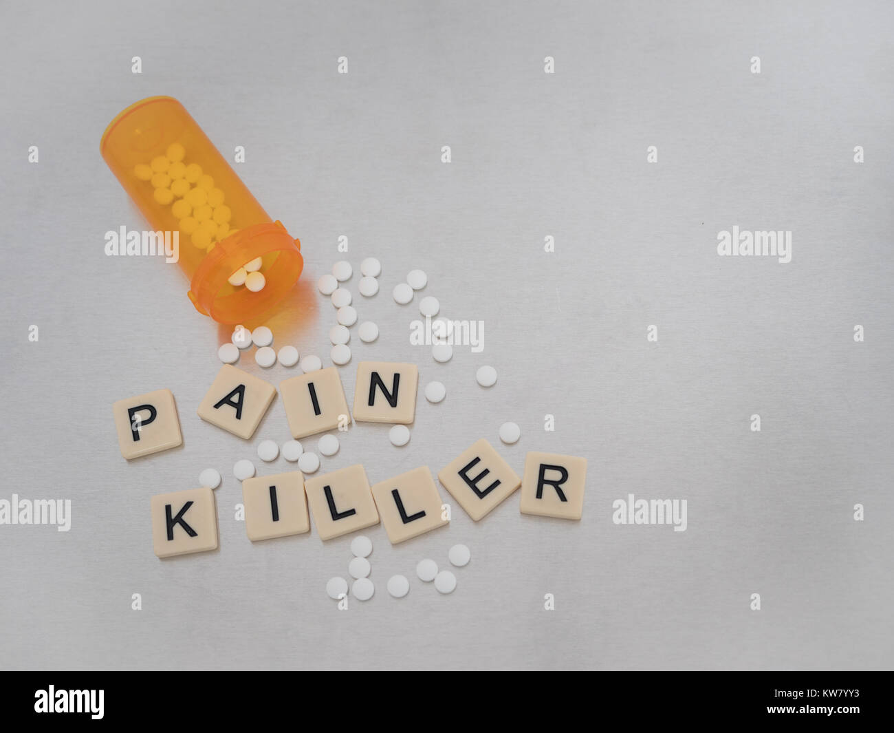 " Pain Killer" scritto con tan piastrelle in plastica e lettere maiuscole nere in acciaio inossidabile con apertura di prescrizione arancione bottiglia di pastiglie di ossicodone Foto Stock