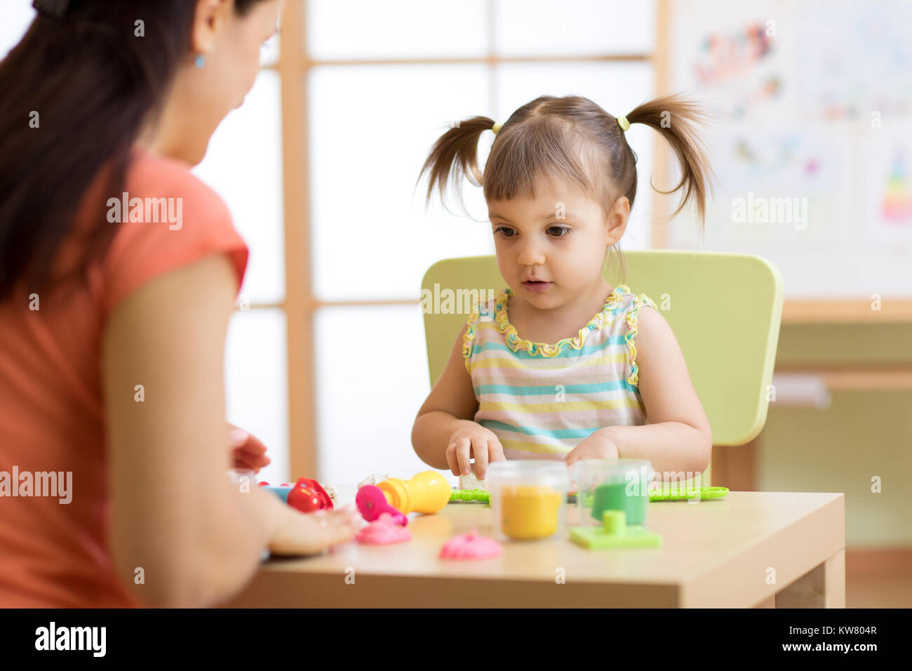 Bambino ragazzo e ragazza madre gioco colorato giocattolo di argilla in vivaio o kindergarten Foto Stock