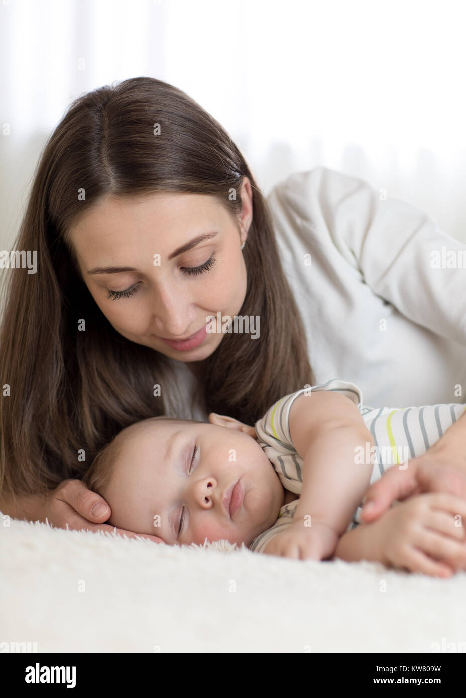 Bella madre guarda 7 mesi il bambino dorme nel letto Foto Stock