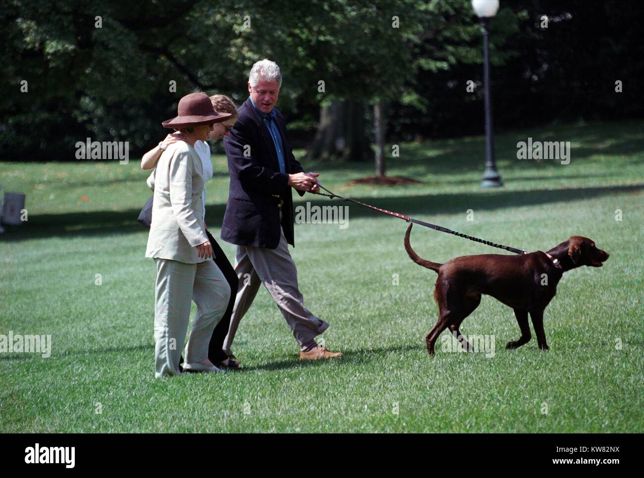 Il presidente William Jefferson Clinton, prima signora Hillary Rodham Clinton e la figlia Chelsea Clinton camminando Buddy il cane in erba, 30 agosto 1998. Foto Stock