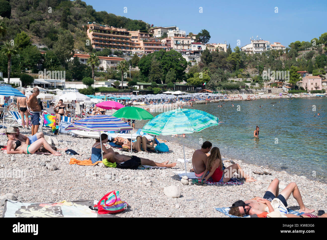 La gente a prendere il sole sulla spiaggia di Mazzarò, Taormina, Sicilia Foto Stock