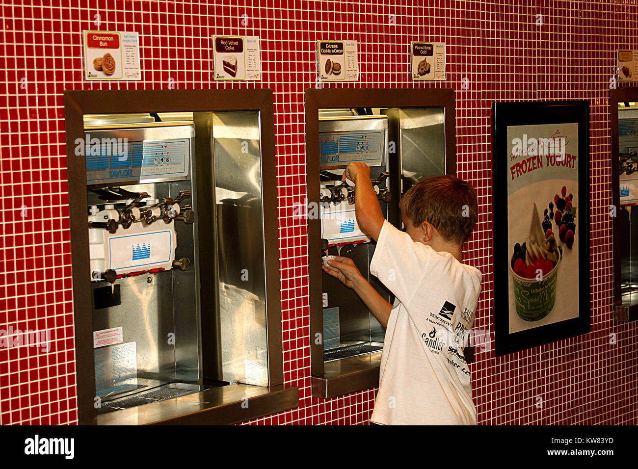 Giovane ragazzo il campionamento frozen yogurt Foto Stock