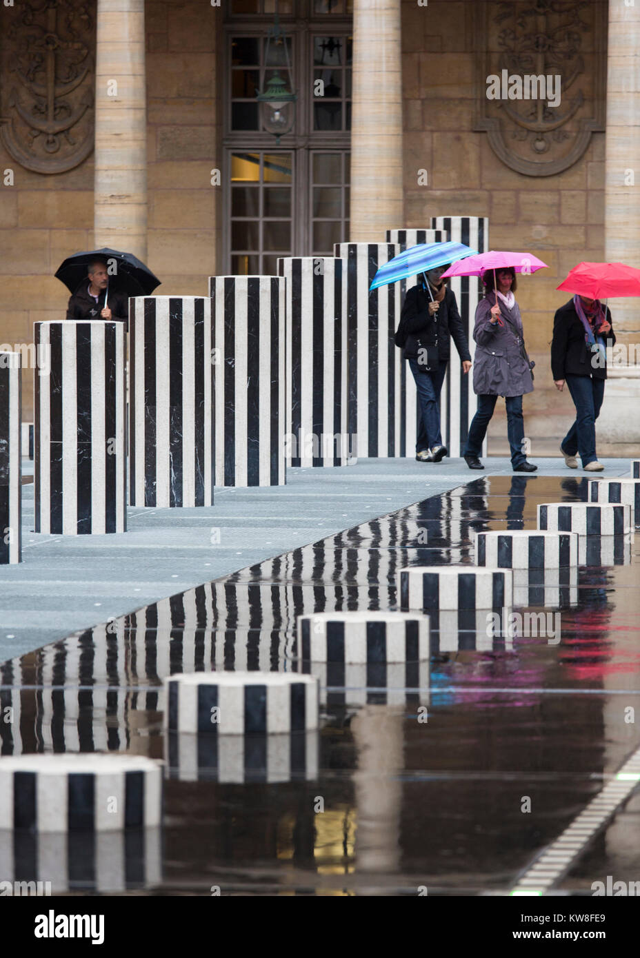 Francia, Parigi (75), ombrelloni a piedi attraverso le colonne di Daniel Buren, artista concettuale. Foto Stock