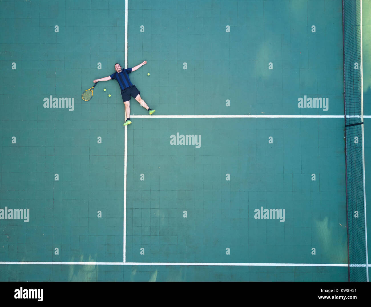 Giocatore di Tennis stanco dopo il gioco e laici sul campo da tennis di vista di cui sopra Foto Stock