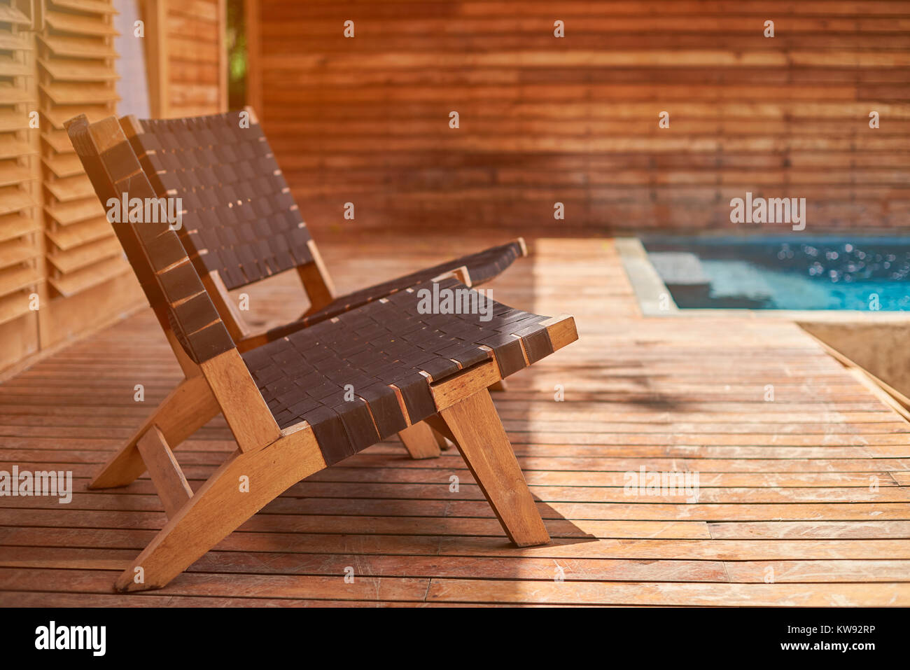 Sedie a sdraio sulla terrazza in legno con il blu acqua di piscina Foto Stock