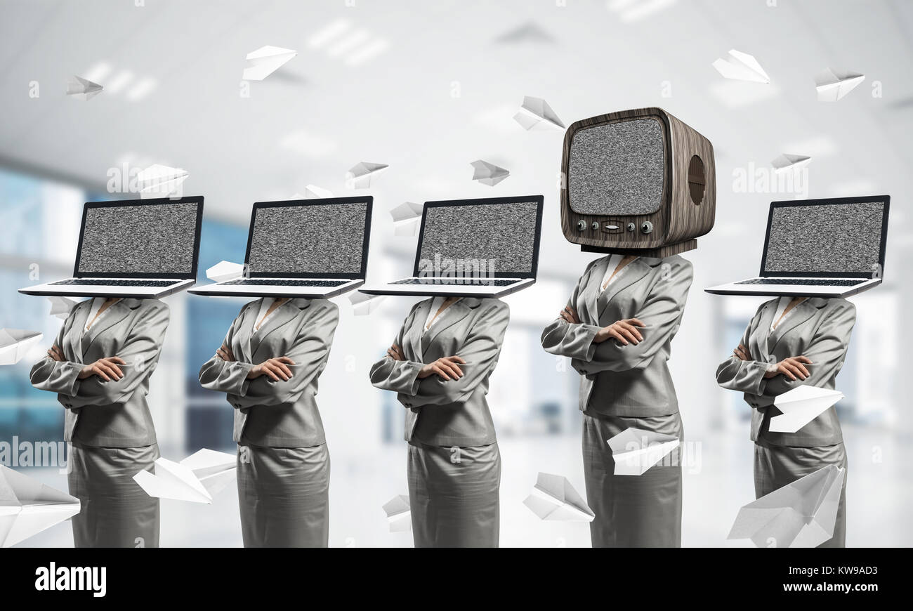 Le donne d'affari in giacca con i laptop invece dei loro capi mantenendo le braccia incrociate mentre sta in piedi in una riga e uno in testa con il vecchio televisore all'interno di office Foto Stock