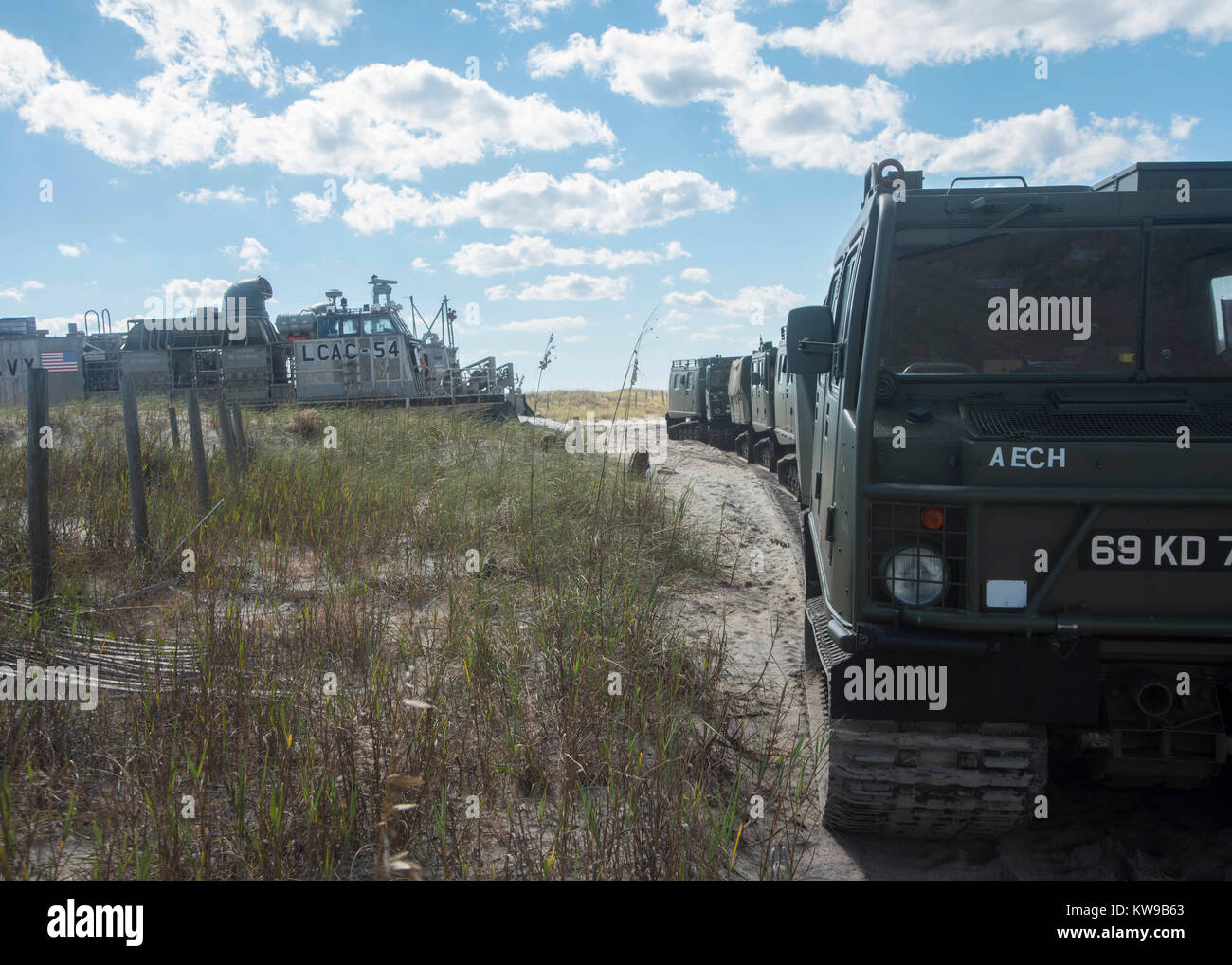 Veicoli blindati folle su di una spiaggia dopo l'offload dalla Landing Craft Air Cushion (LCAC) 54, attache Foto Stock
