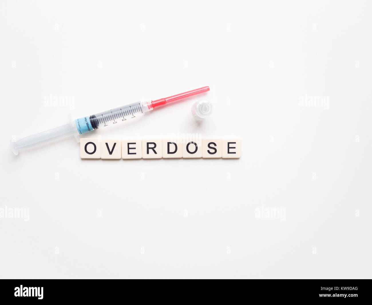 Overdose scritto con lettere di piastrelle collocato in una riga con una siringa riempita con liquido chiaro, fentanil, guarnita con ago rosso. Foto Stock