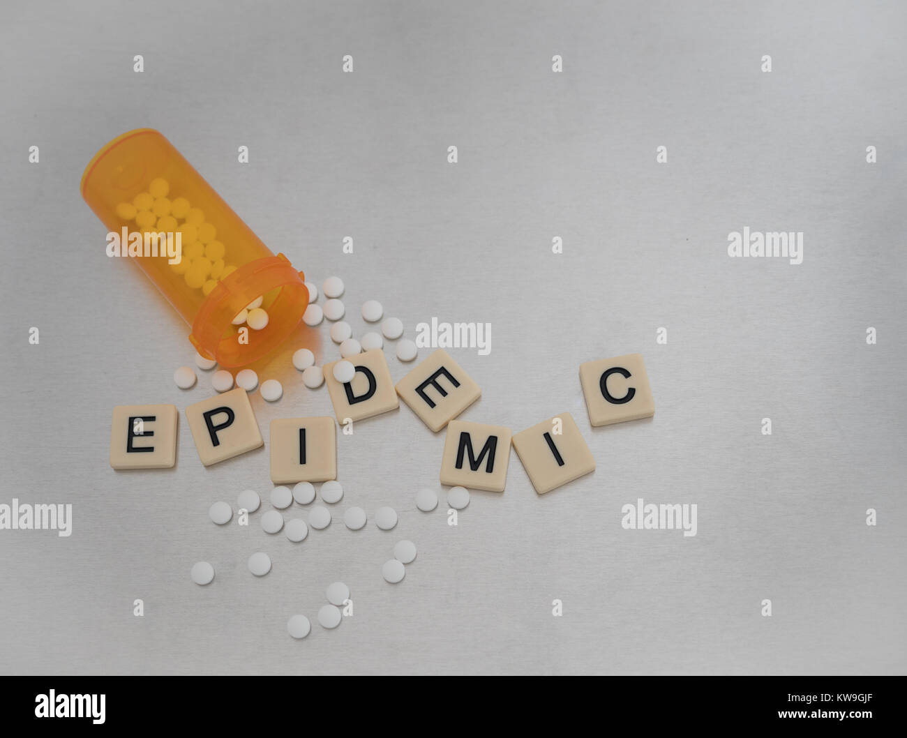Epidemia scritto con lettere di piastrelle in un modello casuale con una bottiglia aperta di ossicodone pillole. Fotografato dal di sopra su un acciaio inossidabile. Foto Stock