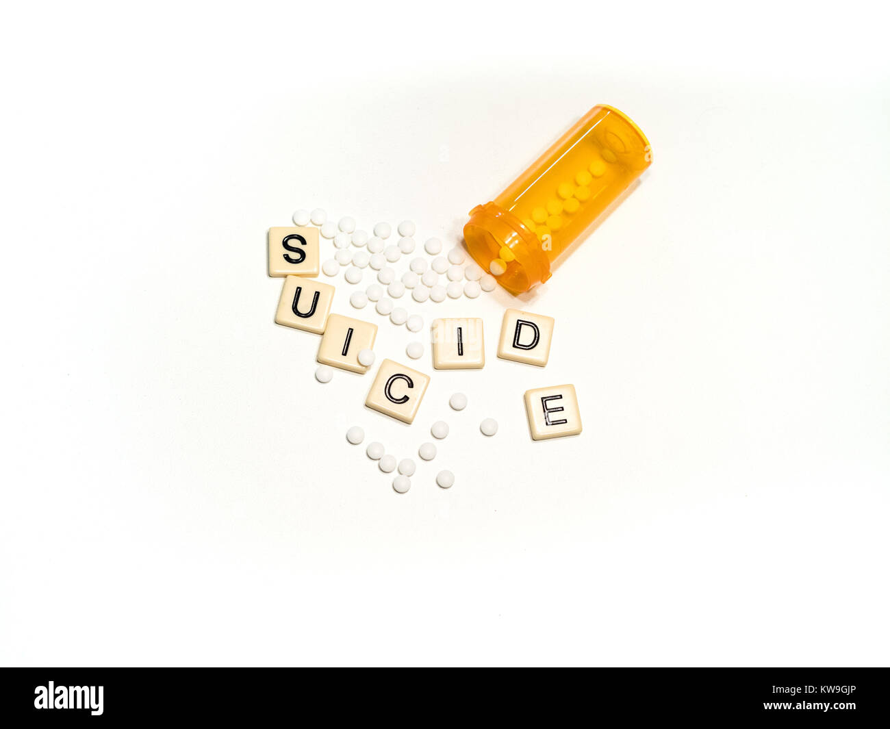 Il suicidio scritto con lettere di piastrelle collocato in un casuale con piccole pillole di bianco e una prescrizione di aprire la bottiglia. Fotografato dal di sopra. Foto Stock