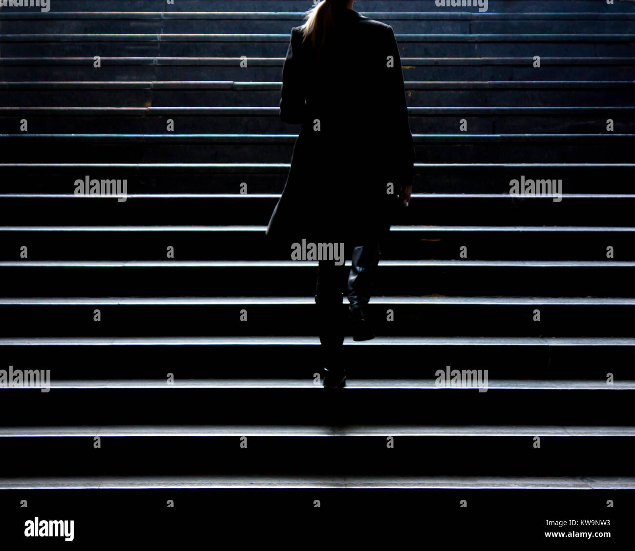Passeggiata urbana : sfocata silhouette della giovane donna elegante salendo per la strada di città scale pubbliche in inverno, da solo , da dietro Foto Stock