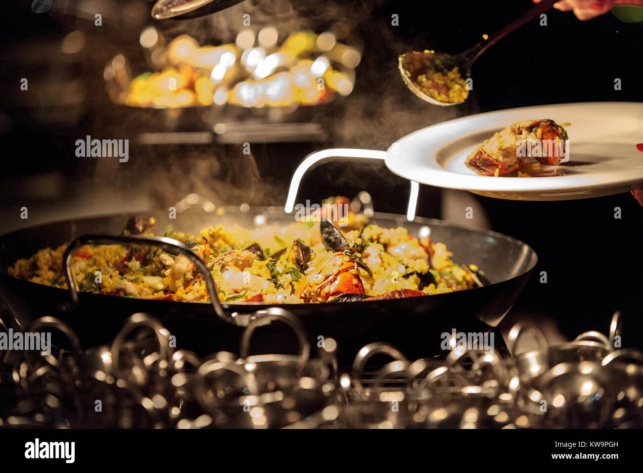 La paella di frutti di mare con gamberetti, capesante, aragosta e muscoli, saltate in padella su di un fornello da cucina Foto Stock