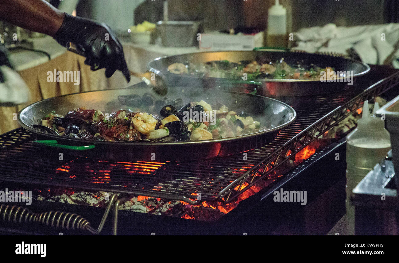 La paella di frutti di mare con gamberetti, capesante, aragosta e muscoli, saltate in padella su di un fornello da cucina Foto Stock