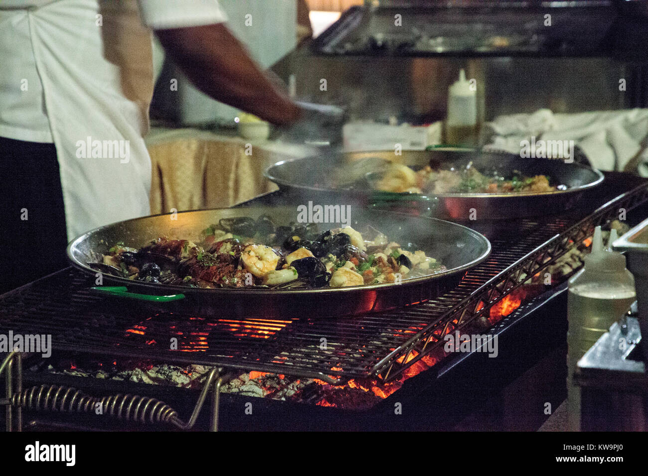 La paella di frutti di mare con gamberetti, capesante, aragosta e muscoli, saltate in padella su di un fornello da cucina Foto Stock