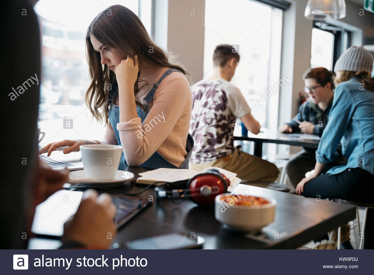 Focalizzato,grave high school girl studente al computer portatile in cafe Foto Stock