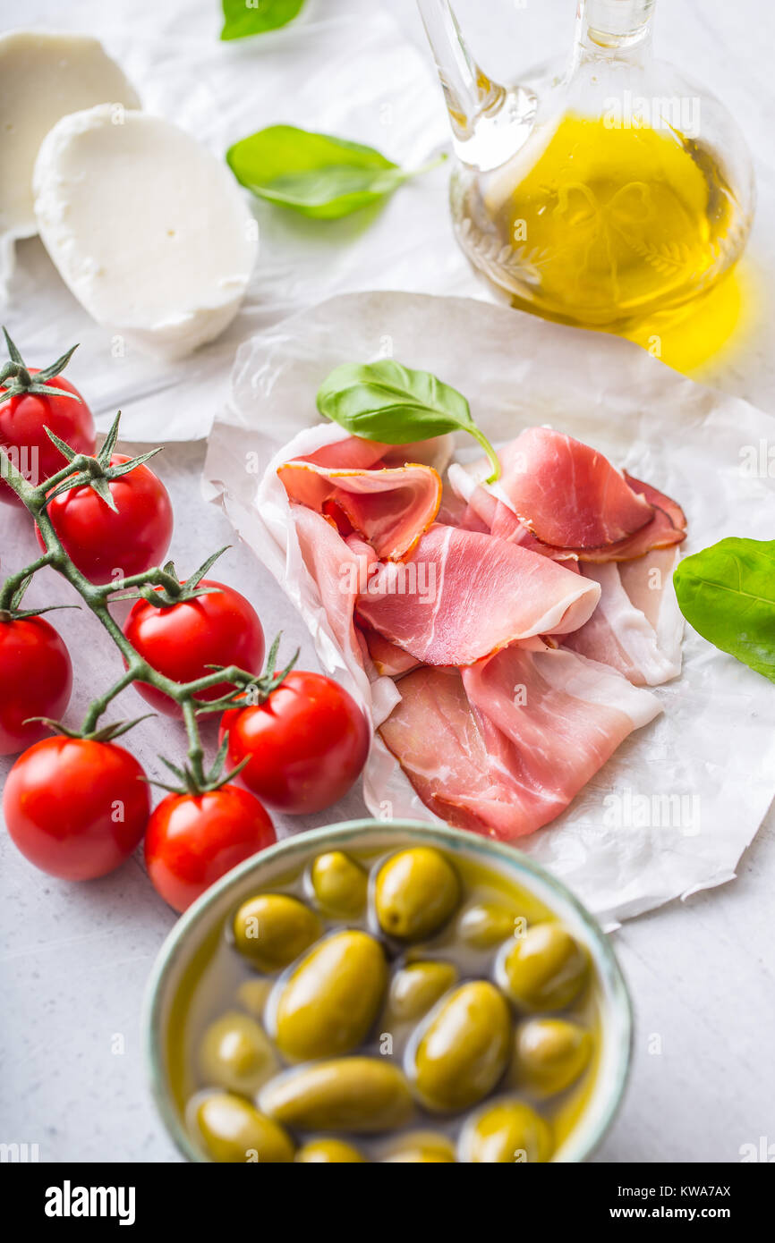 Il Prosciutto Olive Olio d'oliva mozzarella pomodori basilico - ingredienti italiani o cucina mediterranea. Foto Stock