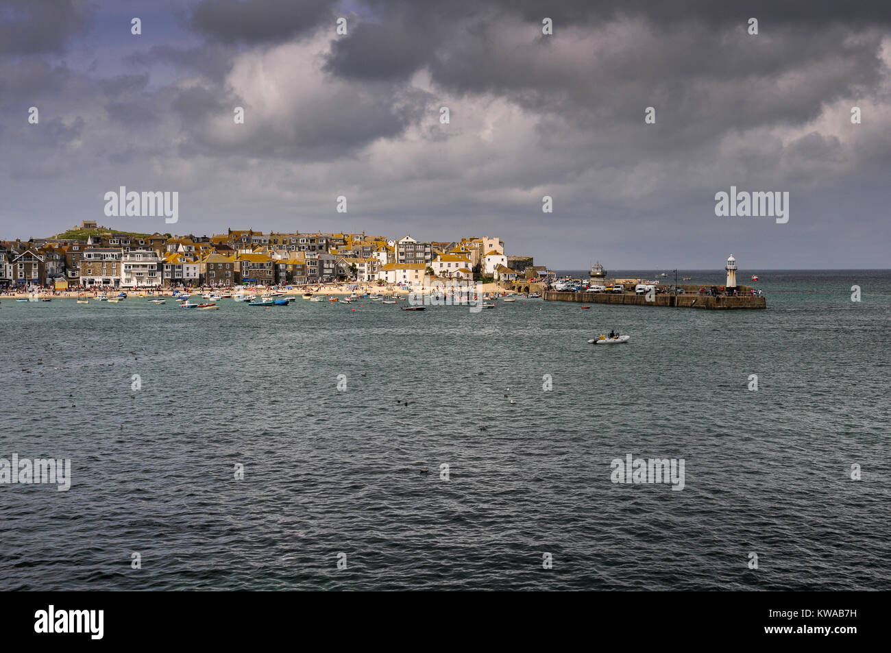 Una veduta distante di fronte al piccolo Cornish località balneare di St Ives, popolare con artisti, con una piccola barca in primo piano, Cornwall, Regno Unito Foto Stock