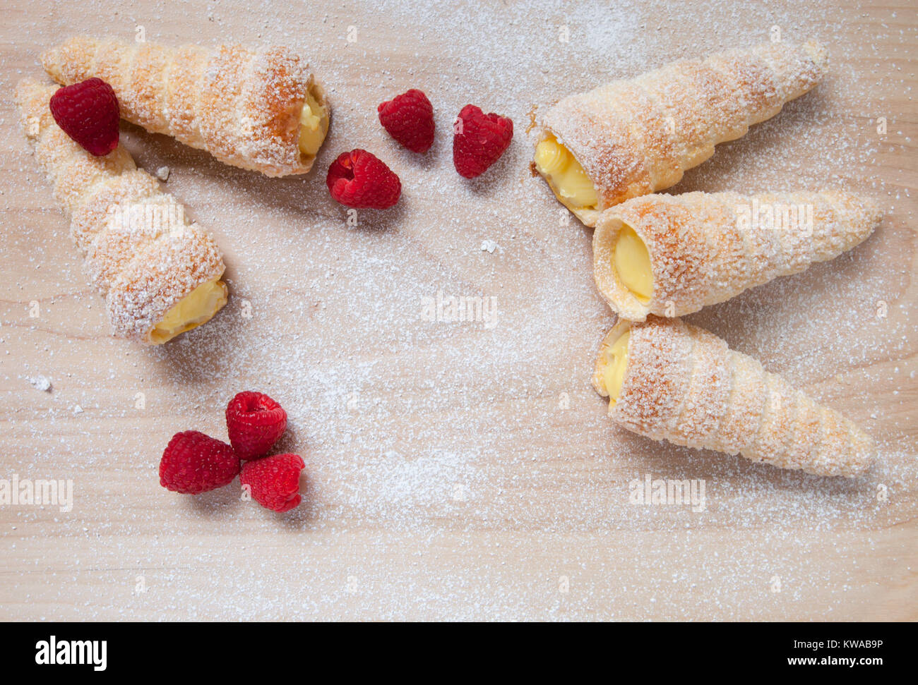 Pasta sfoglia le corna di vaniglia e lamponi su una tavola di legno Foto Stock