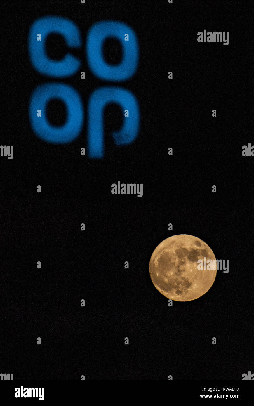 Leominster, UK. 1a gen, 2018. Regno Unito Meteo. La prima luna dell'anno e anche il primo supermoon dell'anno il lupo Luna è visibile al di sotto di una cooperativa store segnale illuminato il 1 gennaio 2018. Credito: Jim legno/Alamy Live News Foto Stock