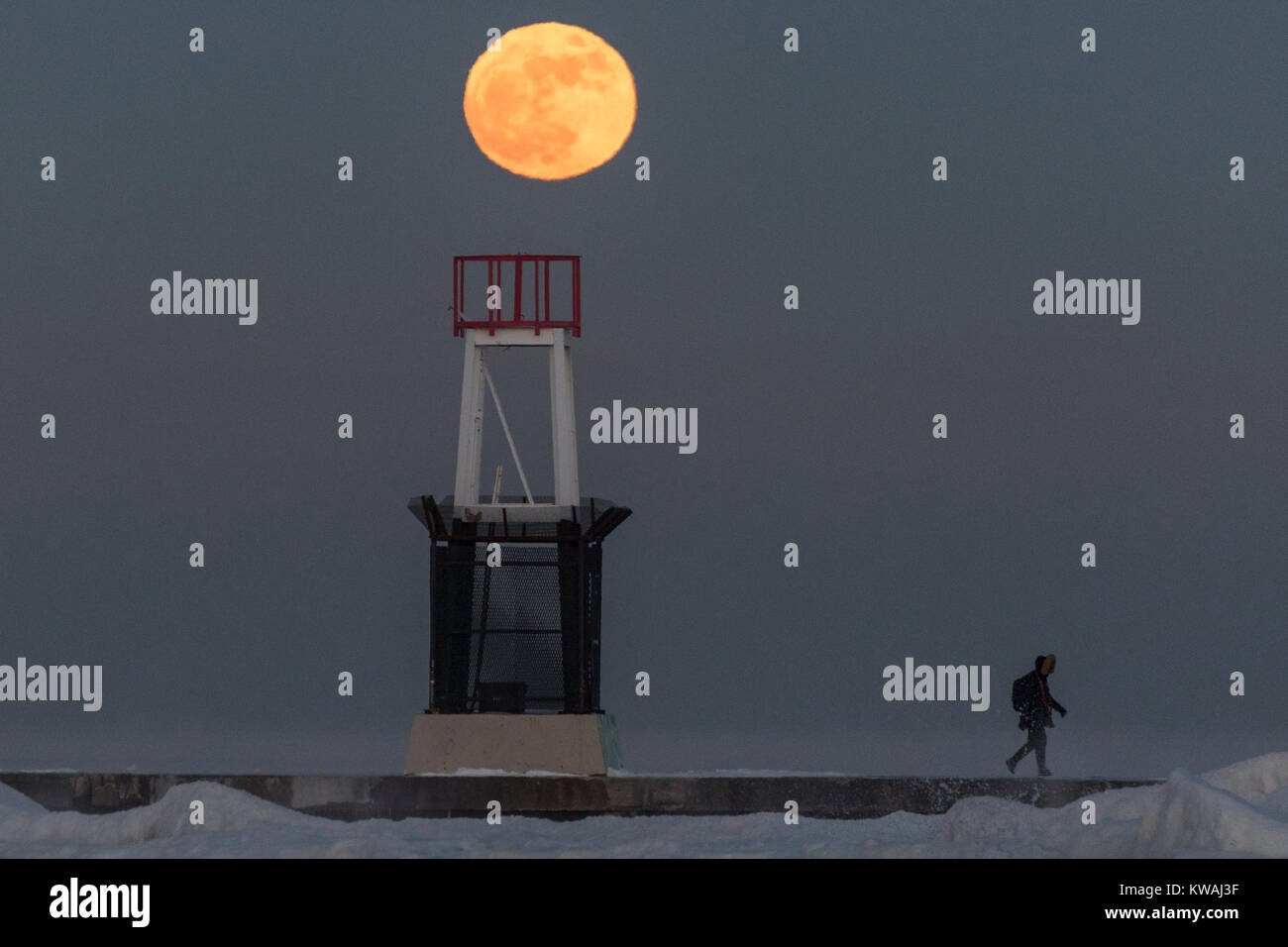 Chicago, Stati Uniti d'America. 1a gen, 2018. Un uomo cammina attraverso il molo al coperto di ghiaccio North Avenue beach come supermoon sorge su una delle più fredde Capodanno in decenni. La luna è al suo punto più vicino, il perigeo, a terra durante la sua orbita mensile e compare il 30% più luminoso e 14% più grande. Gennaio 2018 vede un supermoon noto come 'Wolf moon" il 1 gennaio e un "Blue Moon" il 31 gennaio. Credito: Stephen Chung/Alamy Live News Foto Stock