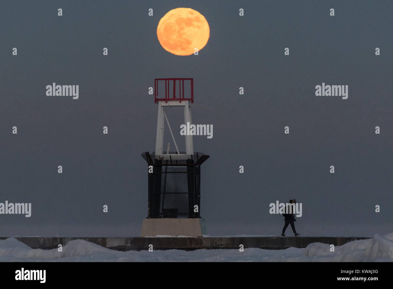 Chicago, Stati Uniti d'America. 1a gen, 2018. Un uomo cammina attraverso il molo al coperto di ghiaccio North Avenue beach come supermoon sorge su una delle più fredde Capodanno in decenni. La luna è al suo punto più vicino, il perigeo, a terra durante la sua orbita mensile e compare il 30% più luminoso e 14% più grande. Gennaio 2018 vede un supermoon noto come 'Wolf moon" il 1 gennaio e un "Blue Moon" il 31 gennaio. Credito: Stephen Chung/Alamy Live News Foto Stock