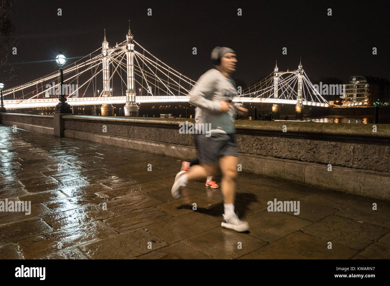Londra, Regno Unito. 02Jan, 2018. Un uomo di jogging sul marciapiede vicino a Albert Bridge in una piovosa notte a Londra. Foto Data: Martedì, 2 gennaio 2018. Credito: Roger Garfield/Alamy Live News Foto Stock