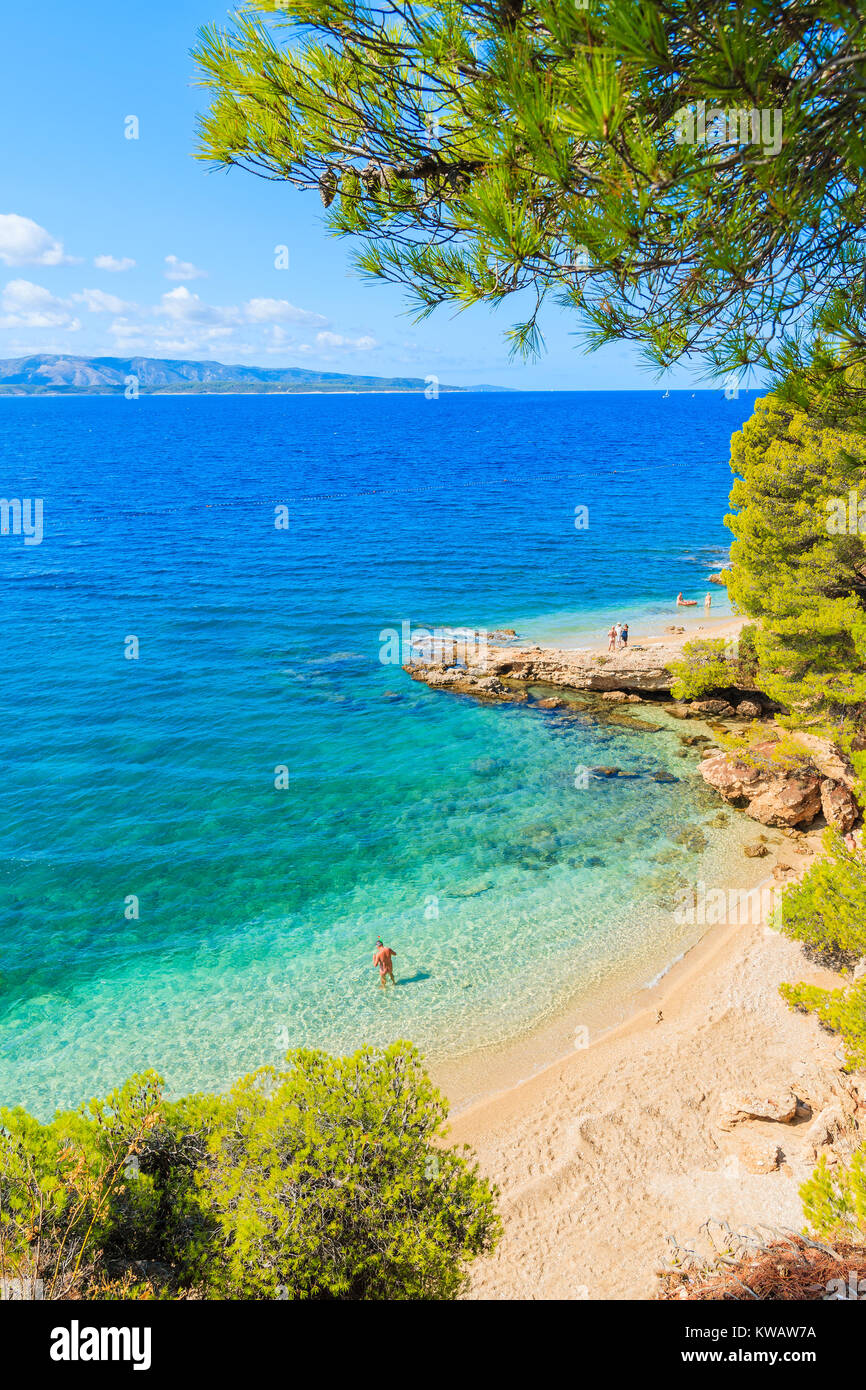 Unidentified man standing in acqua vicino la famosa spiaggia Zlatni Rat nella città di Bol, isola di Brac, Croazia Foto Stock